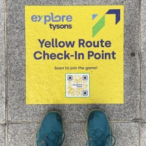 Person's shoes next to explore tysons Yellow Route Check-in Point game square